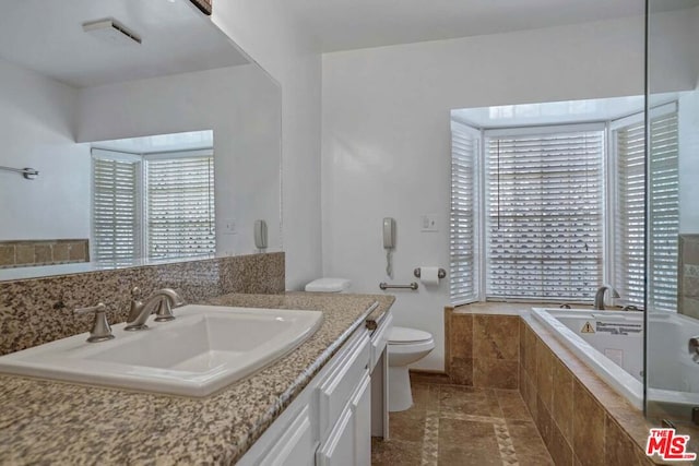 bathroom featuring tile patterned floors, tiled tub, vanity, and toilet