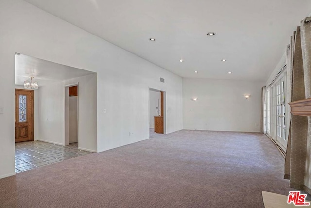 spare room featuring a chandelier and light colored carpet