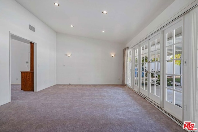 carpeted empty room featuring french doors and vaulted ceiling