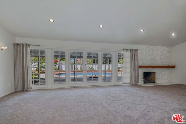 unfurnished living room with a stone fireplace and carpet floors