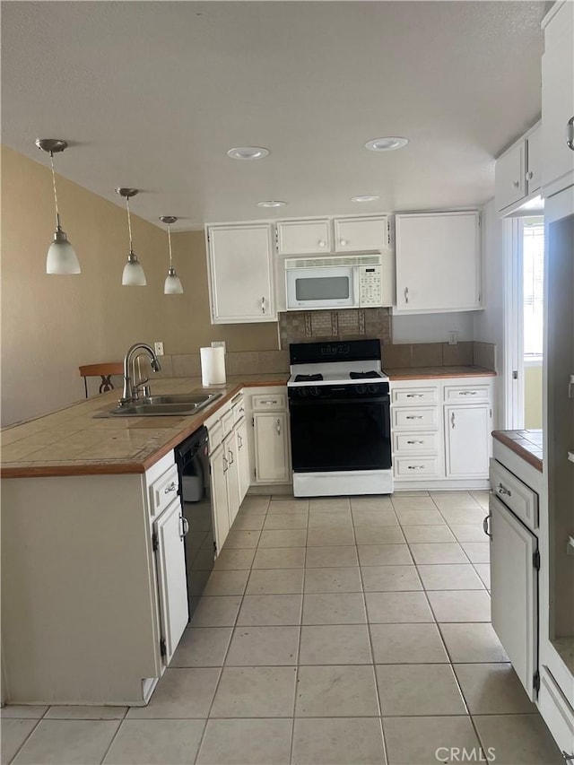 kitchen with kitchen peninsula, white appliances, sink, white cabinetry, and hanging light fixtures