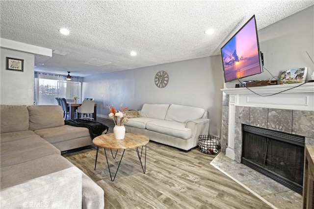 living room with wood-type flooring, a textured ceiling, and a tiled fireplace