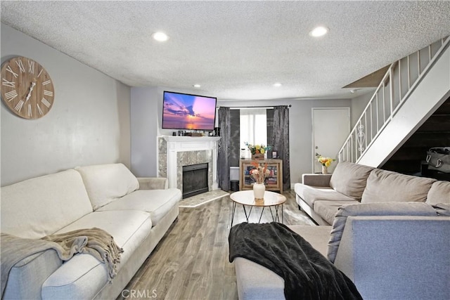 living room with hardwood / wood-style flooring, a textured ceiling, and a high end fireplace