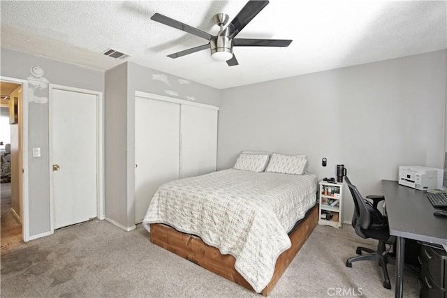 bedroom featuring light carpet, a textured ceiling, a closet, and ceiling fan