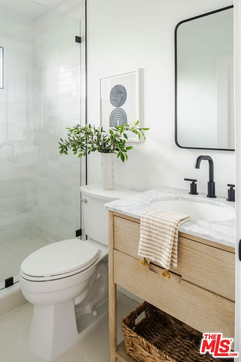 bathroom with tile patterned flooring, vanity, toilet, and a shower with door