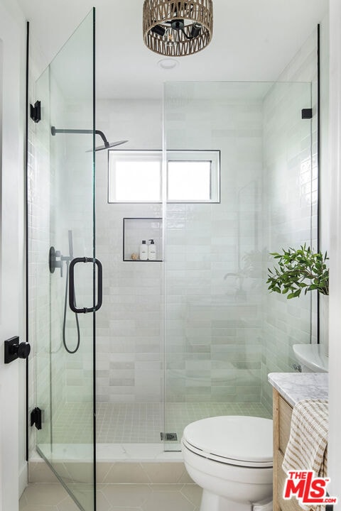 bathroom featuring toilet, vanity, tile patterned floors, and an enclosed shower