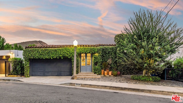 view of front of property featuring a garage, a mountain view, and french doors