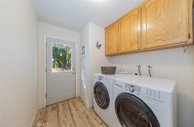 laundry area with cabinets, light hardwood / wood-style floors, and washing machine and clothes dryer