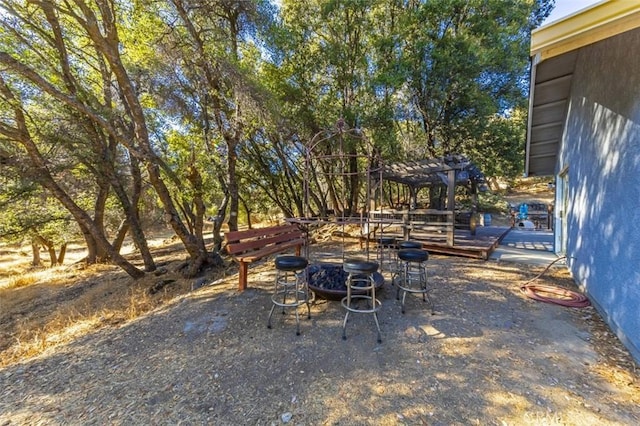 view of yard featuring a pergola, an outdoor fire pit, and a wooden deck