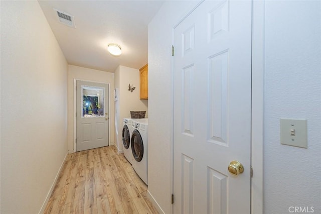 washroom with cabinets, light wood-type flooring, and washing machine and dryer