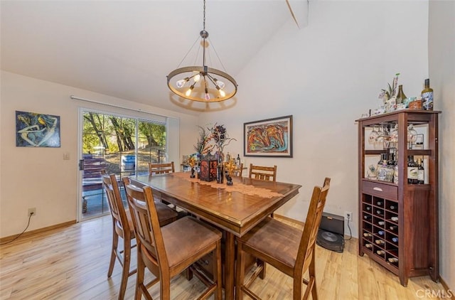 dining space featuring light hardwood / wood-style flooring, high vaulted ceiling, and a notable chandelier