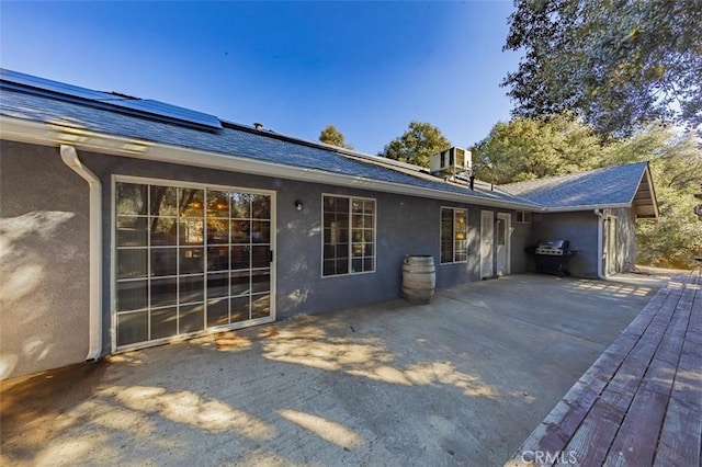 back of property with solar panels, a deck, and central air condition unit