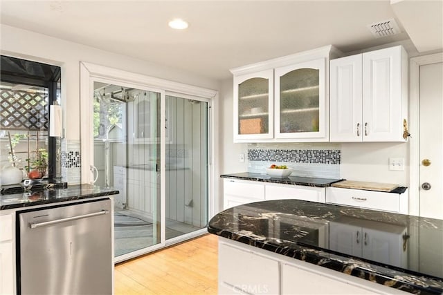 kitchen with white cabinetry, dishwasher, tasteful backsplash, light hardwood / wood-style flooring, and dark stone counters