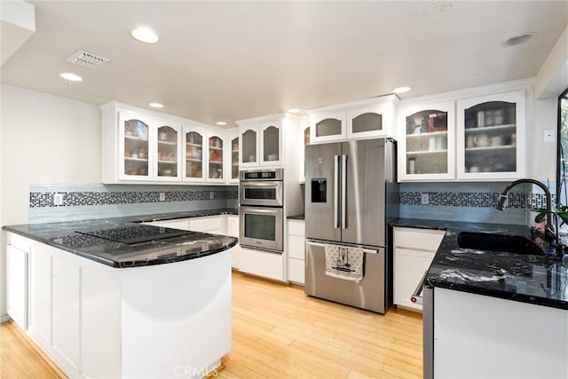 kitchen with kitchen peninsula, stainless steel appliances, white cabinetry, and sink