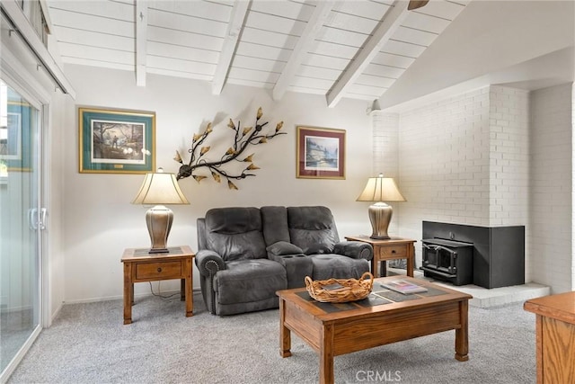 carpeted living room with vaulted ceiling with beams, a wood stove, and wooden ceiling