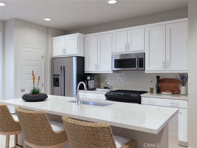 kitchen with sink, a kitchen bar, stainless steel appliances, and an island with sink