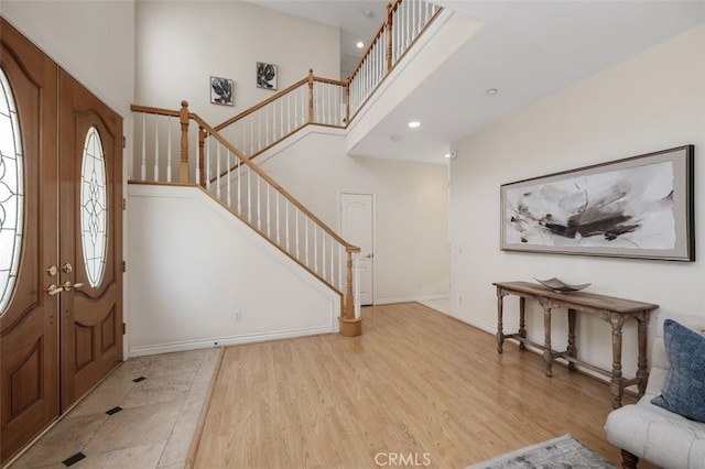 foyer featuring light wood-type flooring, a high ceiling, and french doors