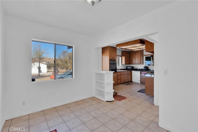 kitchen featuring light tile patterned floors, white dishwasher, and black oven