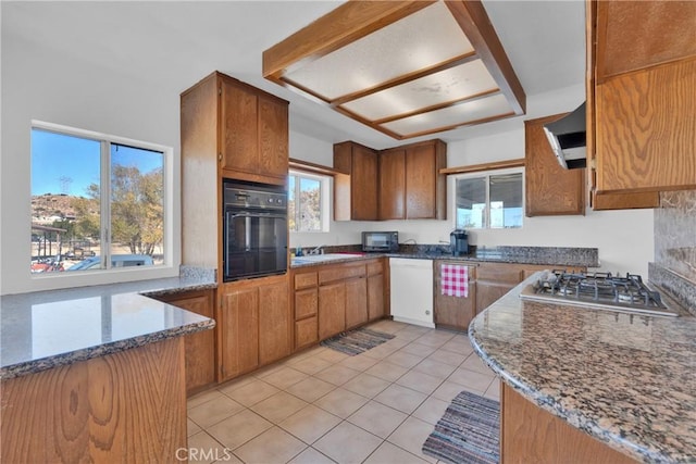 kitchen featuring exhaust hood, light tile patterned flooring, dark stone countertops, and black appliances