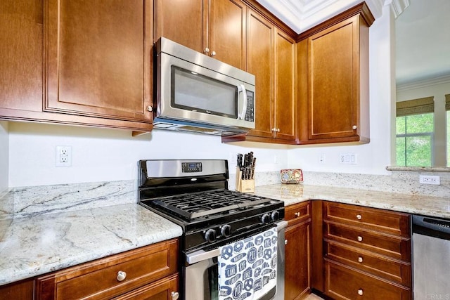 kitchen with crown molding, light stone countertops, and stainless steel appliances