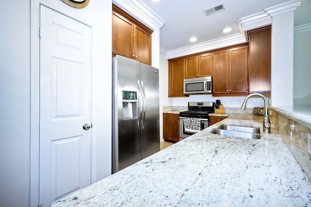 kitchen featuring appliances with stainless steel finishes, ornate columns, light stone counters, crown molding, and sink