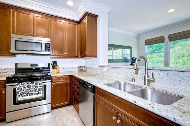 kitchen with sink, stainless steel appliances, light stone counters, light tile patterned floors, and ornamental molding