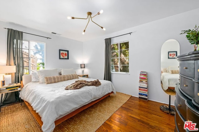 bedroom featuring an inviting chandelier and dark wood-type flooring