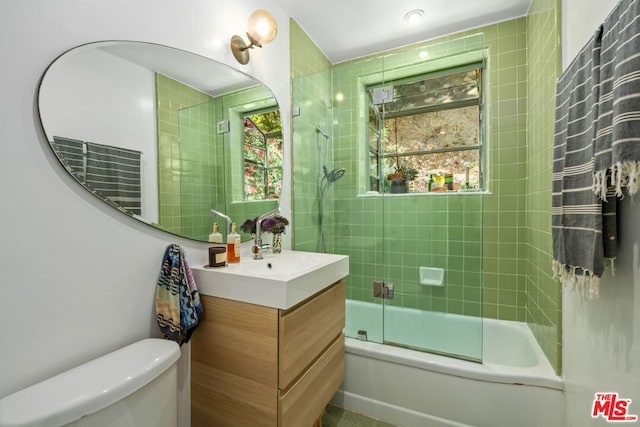 full bathroom featuring vanity, toilet, a wealth of natural light, and enclosed tub / shower combo