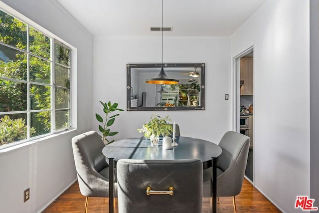 dining area with plenty of natural light, dark wood-type flooring, and ornamental molding