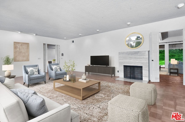 living room with a high end fireplace and a textured ceiling