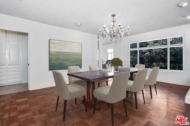 dining area with a chandelier, a textured ceiling, and dark parquet floors