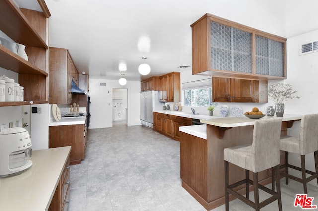 kitchen featuring a kitchen bar, kitchen peninsula, and white fridge