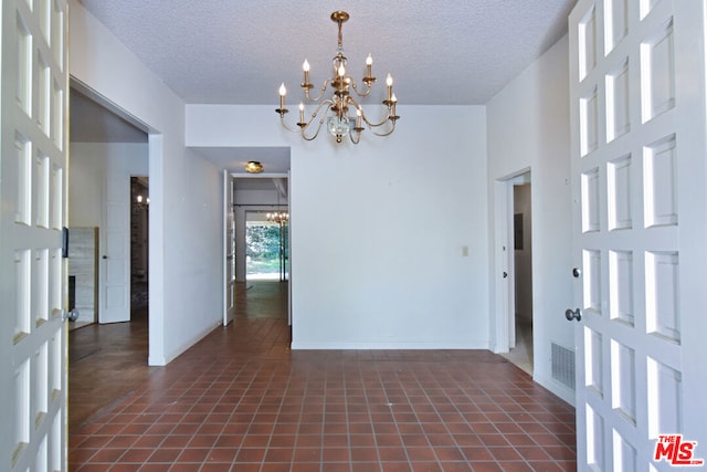 interior space with a chandelier, a high ceiling, a textured ceiling, and dark tile patterned flooring