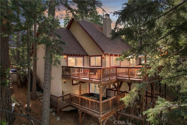 back house at dusk with a wooden deck