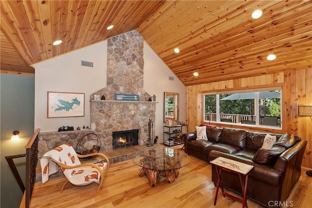 living room with wood ceiling, wooden walls, a fireplace, light wood-type flooring, and high vaulted ceiling