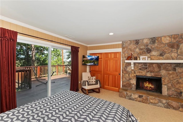 carpeted bedroom featuring crown molding, access to outside, and a stone fireplace