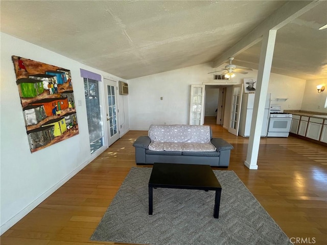 living room with hardwood / wood-style floors, lofted ceiling with beams, a wall unit AC, and french doors