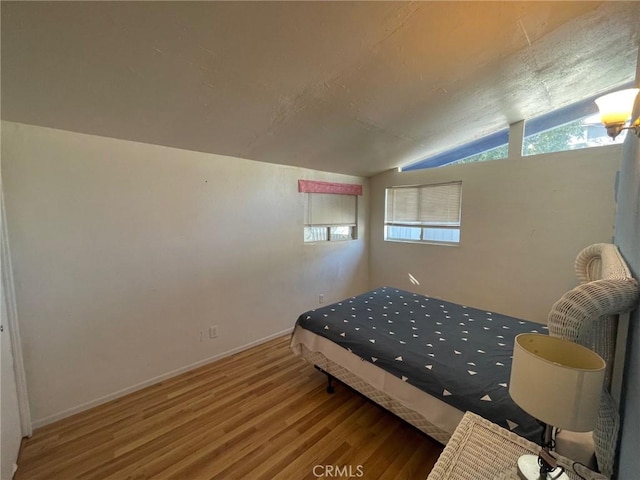 bedroom featuring hardwood / wood-style floors, lofted ceiling, and multiple windows