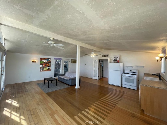 unfurnished living room featuring hardwood / wood-style floors, vaulted ceiling with beams, sink, and a textured ceiling