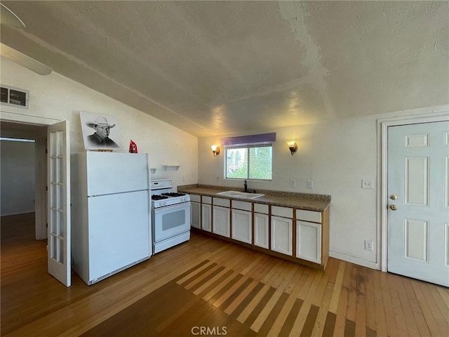 kitchen featuring white appliances, white cabinets, sink, vaulted ceiling, and light wood-type flooring