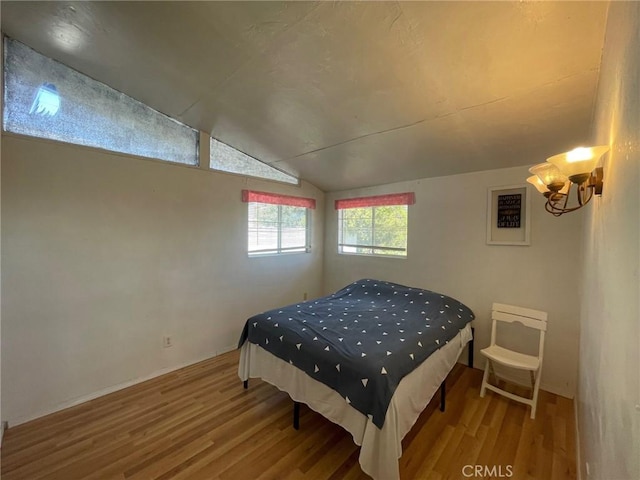 bedroom featuring a chandelier, hardwood / wood-style floors, and lofted ceiling