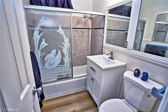 full bathroom featuring tasteful backsplash, bath / shower combo with glass door, vanity, wood-type flooring, and toilet