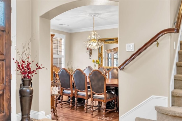 dining area with crown molding, hardwood / wood-style floors, and a notable chandelier