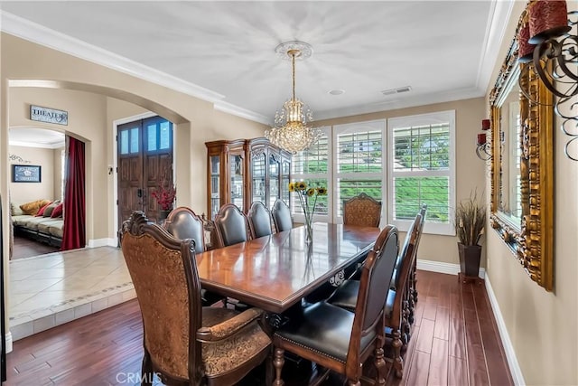 dining space with crown molding, dark wood-type flooring, and a notable chandelier