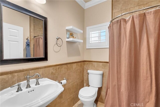 bathroom with toilet, sink, tile walls, and ornamental molding