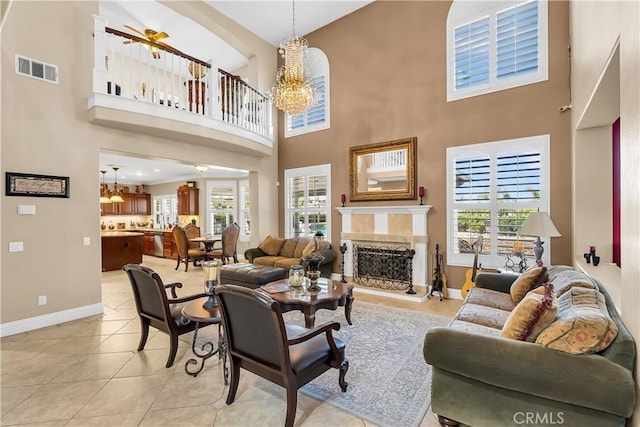 tiled living room featuring a high ceiling and ceiling fan with notable chandelier