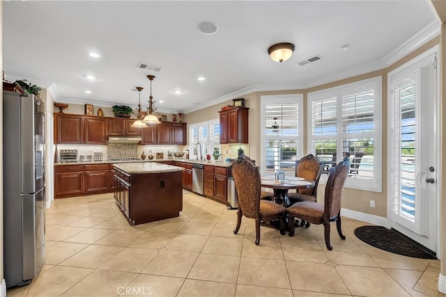 kitchen featuring hanging light fixtures, a kitchen island, stainless steel appliances, and ornamental molding