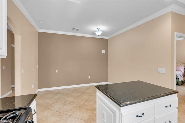 kitchen with dark stone counters, white cabinetry, ornamental molding, and stainless steel range oven