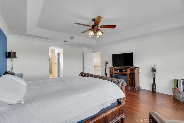 bedroom featuring a raised ceiling, ceiling fan, dark wood-type flooring, and ornamental molding