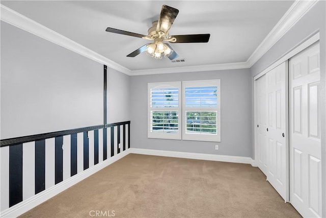 unfurnished bedroom with light carpet, a closet, ceiling fan, and crown molding